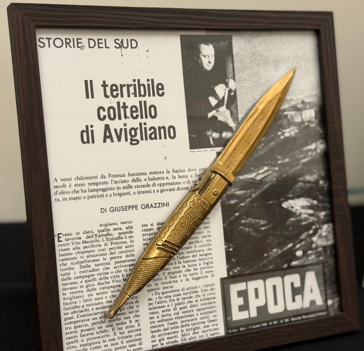 Balestra — coltello in rilievo dorato su collage di pagine di giornale d'epoca, cornice nera