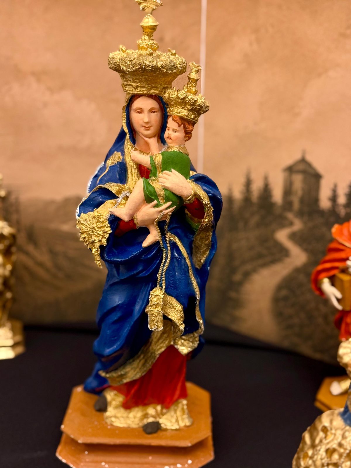 Madonna del Carmine col Bambino, veste policroma dipinta e dorata a mano, sul fondale del santuario